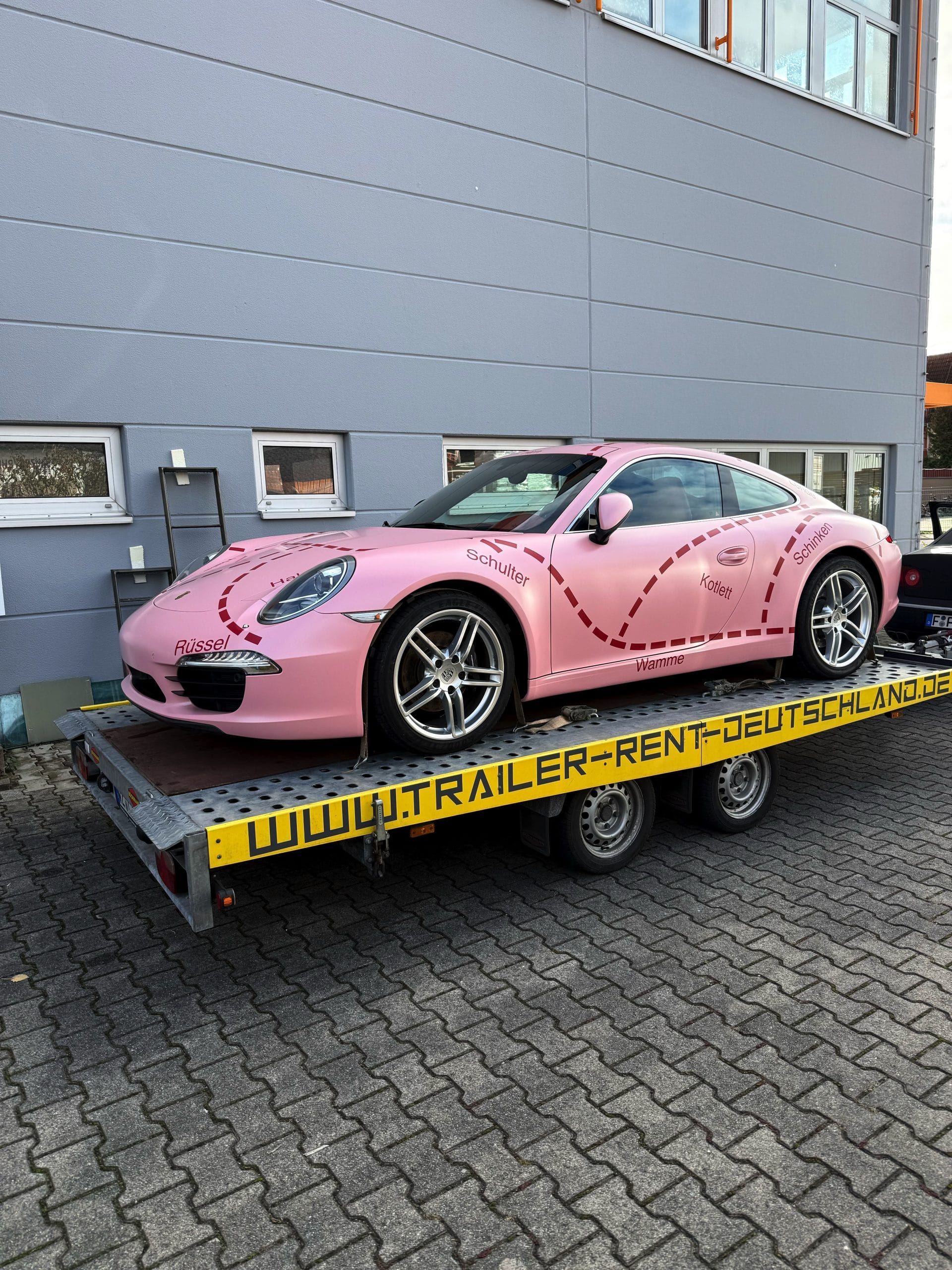 Pinker Porsche 911 auf einem Fahrzeuganhänger bei WrapIndustries