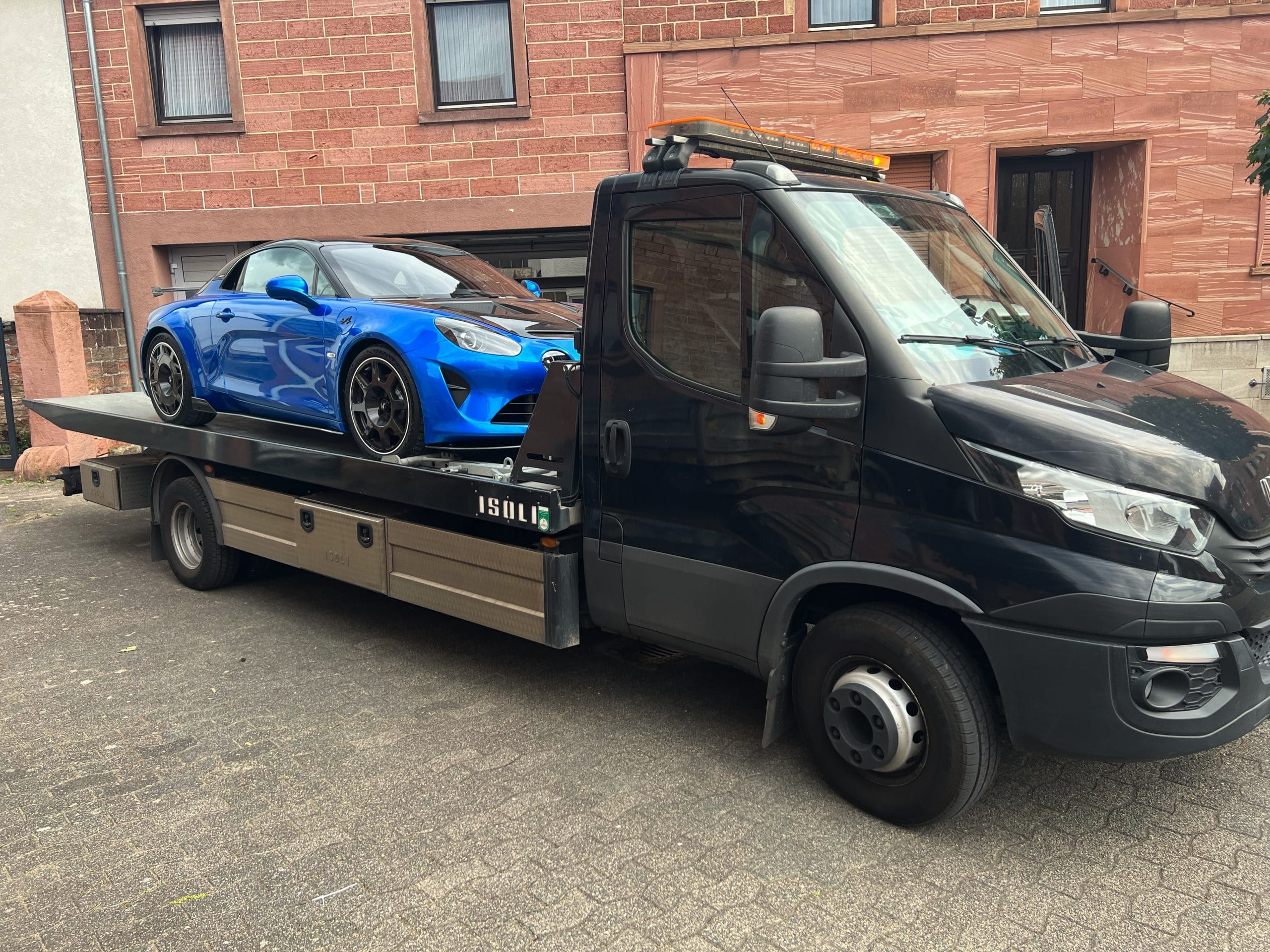 Blauer Alpine A110 auf einem offenen Fahrzeugtransporter
