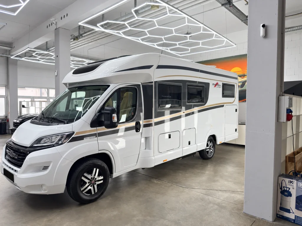 Weißes Wohnmobil in der Werkstatt von WrapIndustries, schräg von vorn links; Kennzeichen unkenntlich.