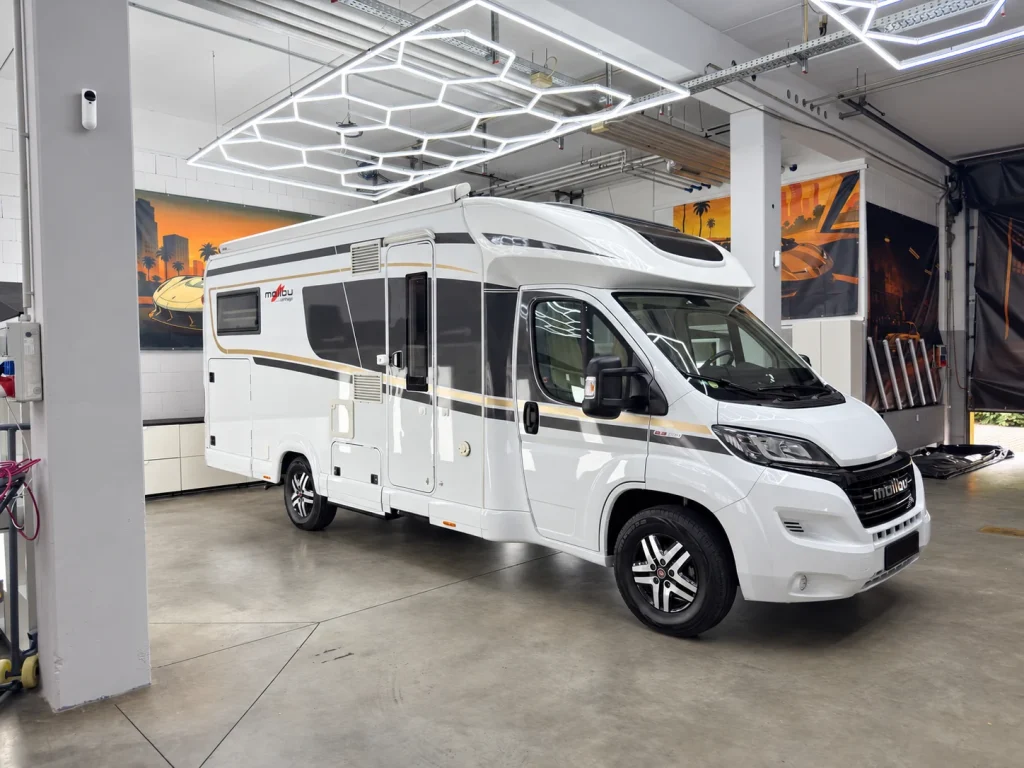 Weißes Wohnmobil in der Werkstatt von WrapIndustries, schräg von vorn rechts; Kennzeichen unkenntlich.