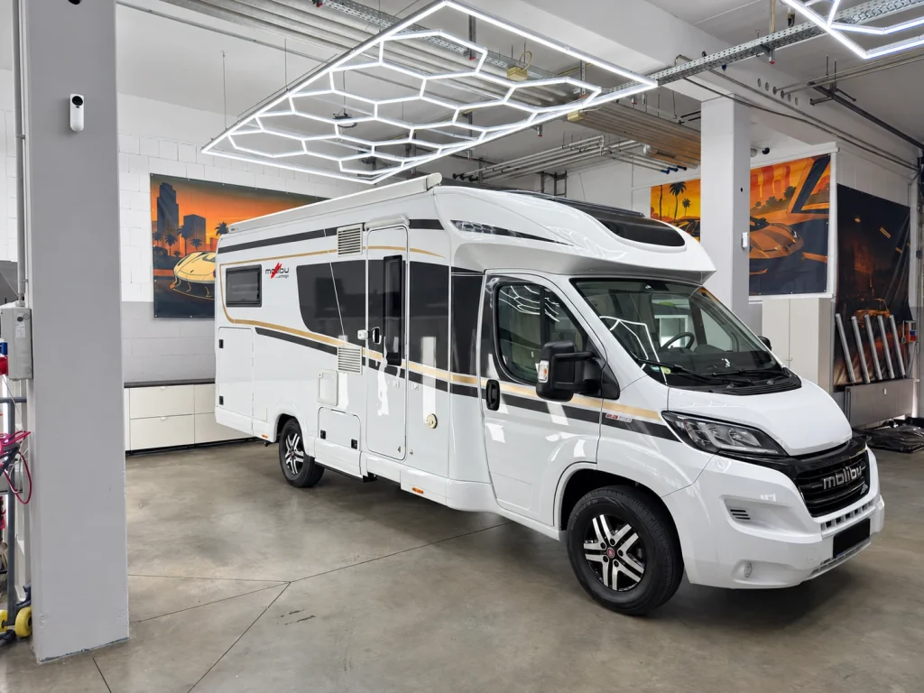 Weißes Wohnmobil in der Werkstatt von WrapIndustries, schräg von vorn rechts; Kennzeichen unkenntlich.